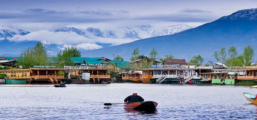 Shikara boat and houseboats on Dal Lake with snow mountains behind, Srinagar